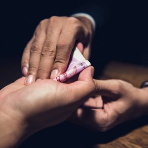 Businessman closing a deal by giving money, Indian rupee banknotes, to his partner in hand - bribery concept